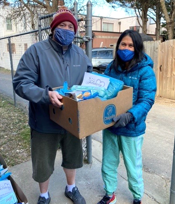 Photo of masked Asian couple holding large boxes of nutritious groceries.