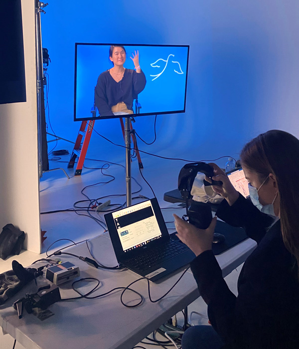 Photo of female-presenting person doing technical preparation for filming