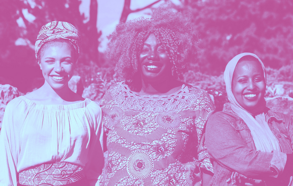 Three smiling Black immigrant women standing side by side.