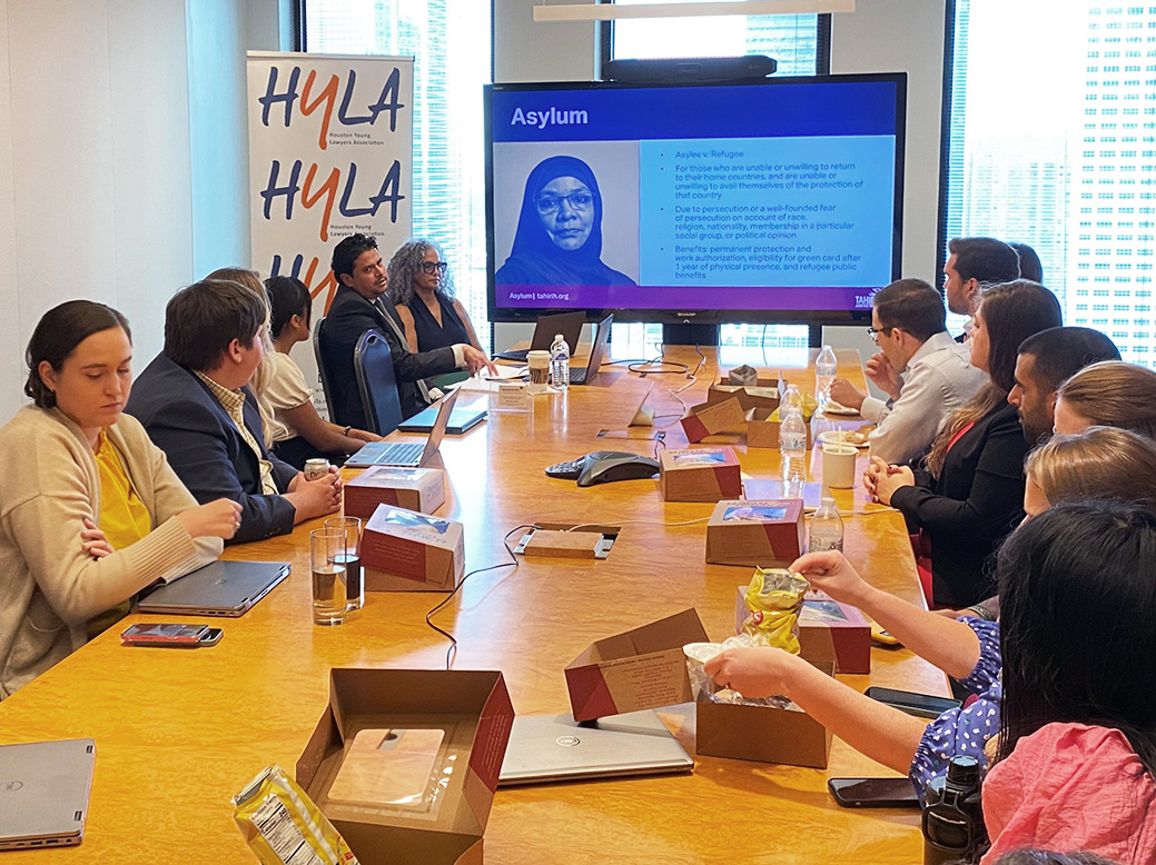 Tahirih staff members sitting around a conference room table looking at a large screen with a presentation slide titled Asylum.