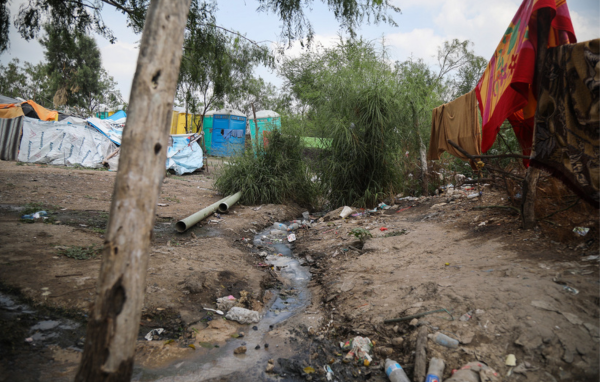 Encampment at the US Mexico border with trash, tents, and portable toilets