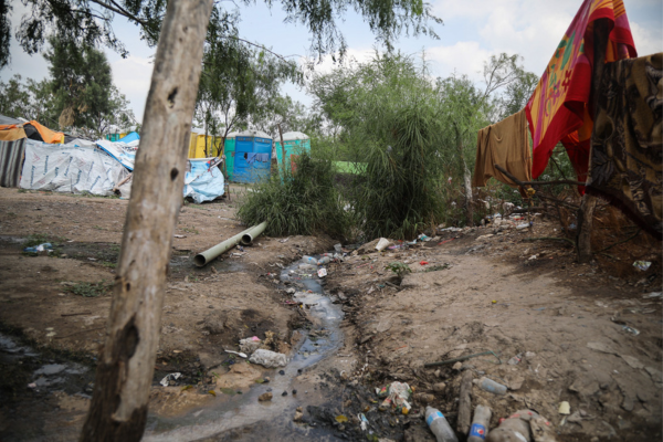 Encampment at the US Mexico border with trash, tents, and portable toilets