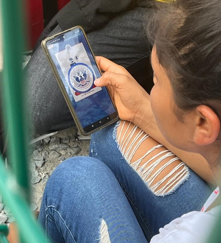 Person holding a cell phone displaying the CBPOne app