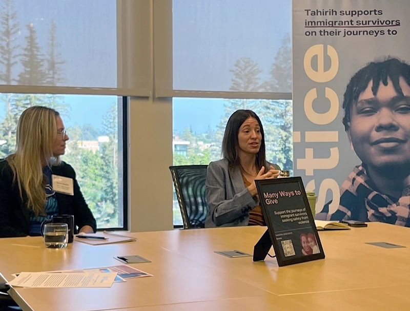 Woman presenting to conference room attendees in front of a Tahirih Justice Center banner.