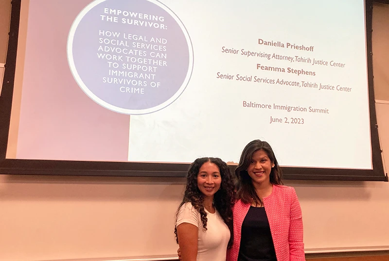 Two women standing in front of presentation screen for the Baltimore Immigration Summit