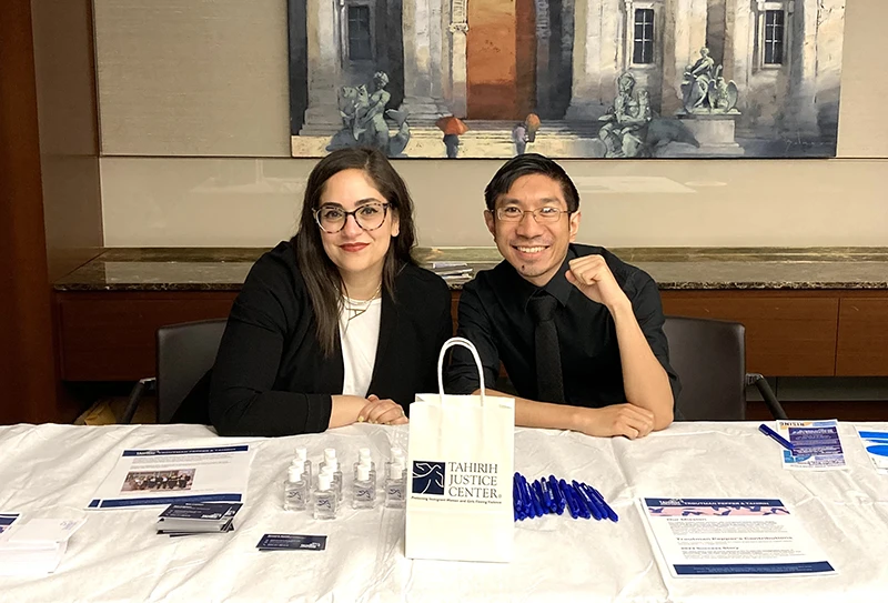 Woman and man sitting behind a table at a law office with Tahirih Justice Center materials.