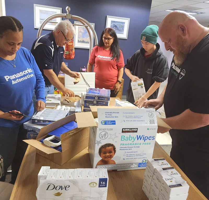 Five people around a table in an office hallway packaging donation materials