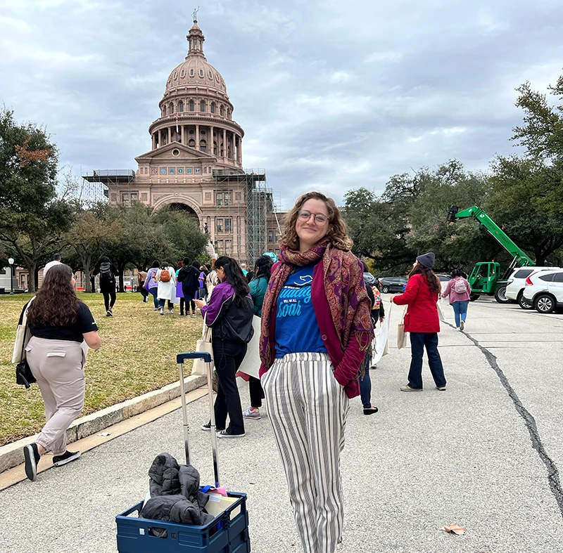 Woman with roll cart for paper files stands in front of state building