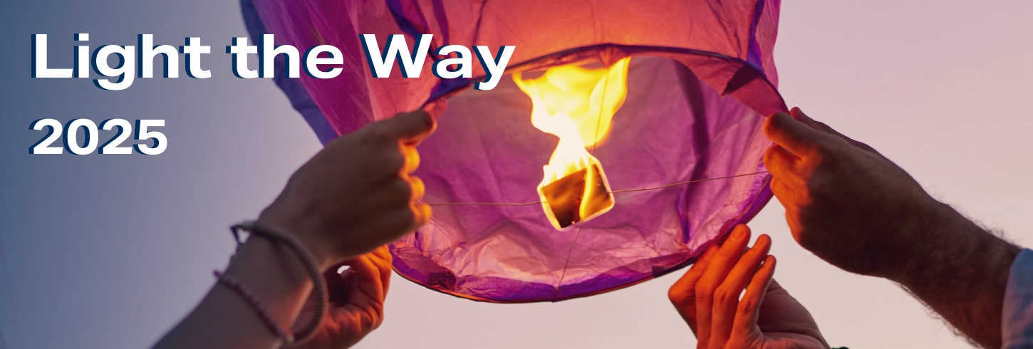 Hands holding up a small hot air balloon with flame inside. Text says Light the Way 2025