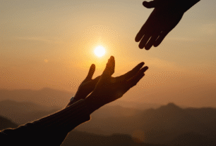 Two hands reaching toward each other in warm sunset light, symbolizing support and hope.