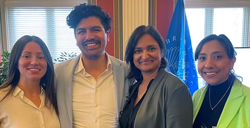 Four professional adults of mixed ethnicity side by side smiling.